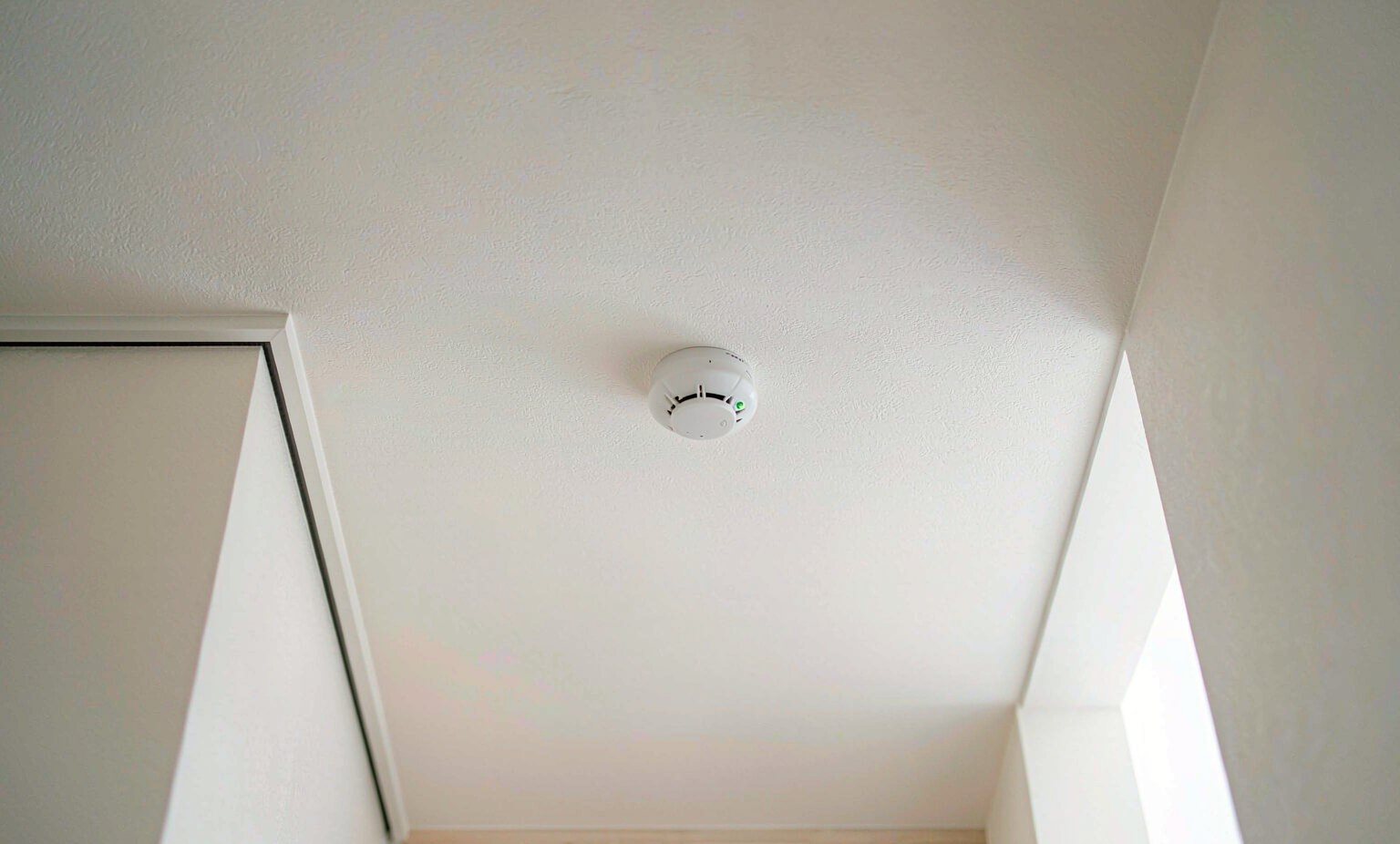 Modern minimalist living room with a white smoke alarm mounted on the ceiling