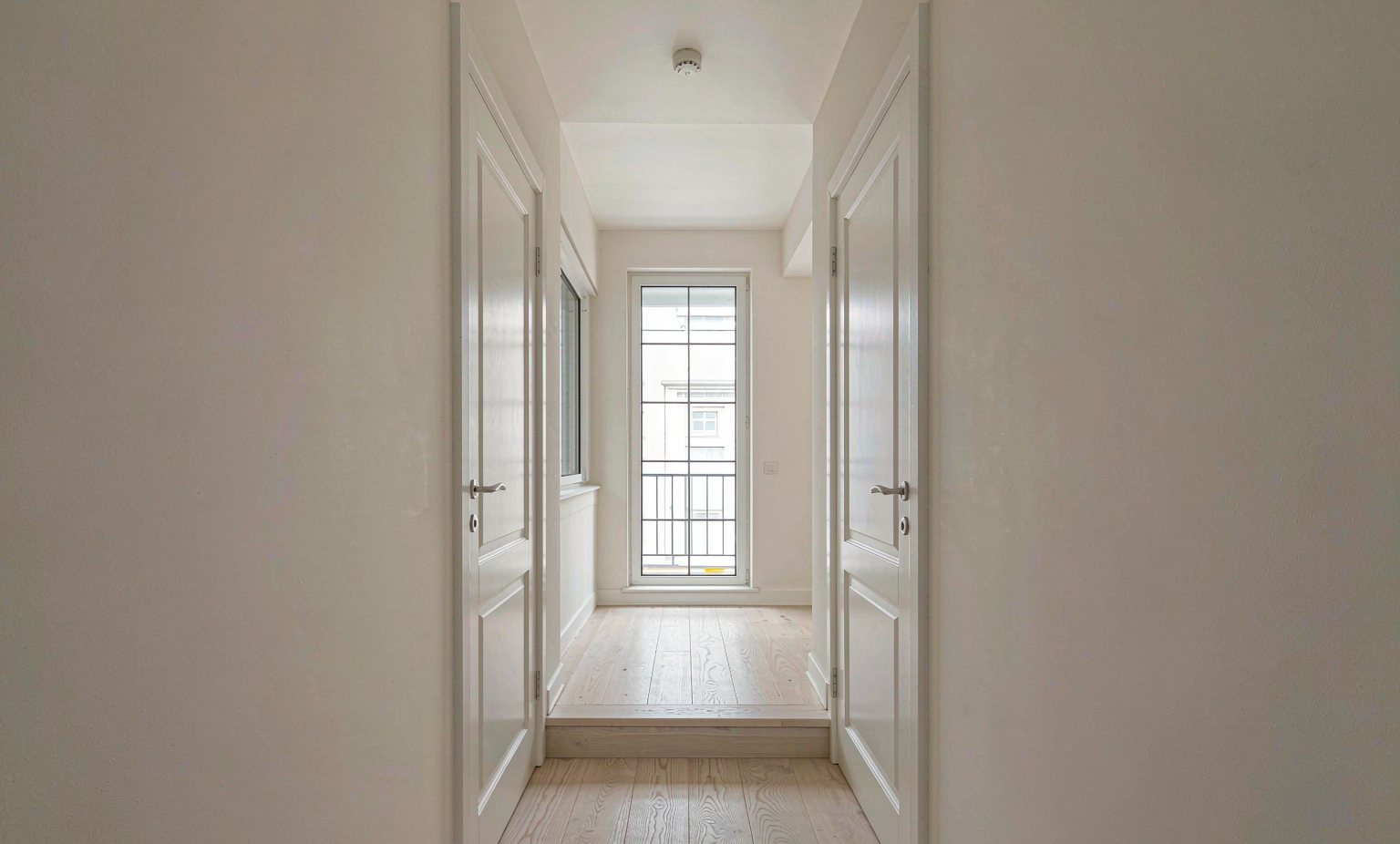 Apartment hallway with a smoke alarm on the ceiling above the bedroom doors
