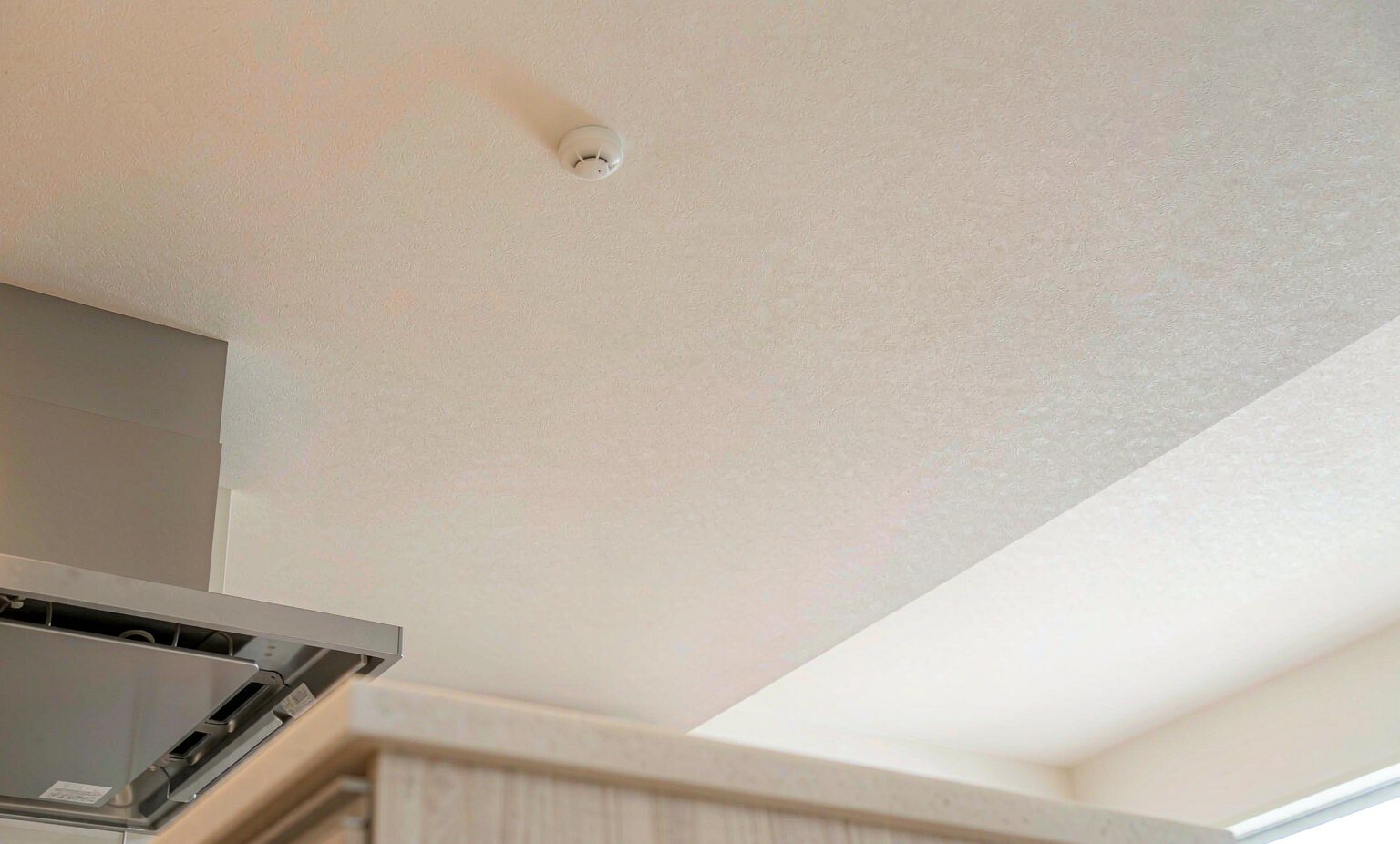 Modern kitchen ceiling with a heat detector installed well away from the cooking area
